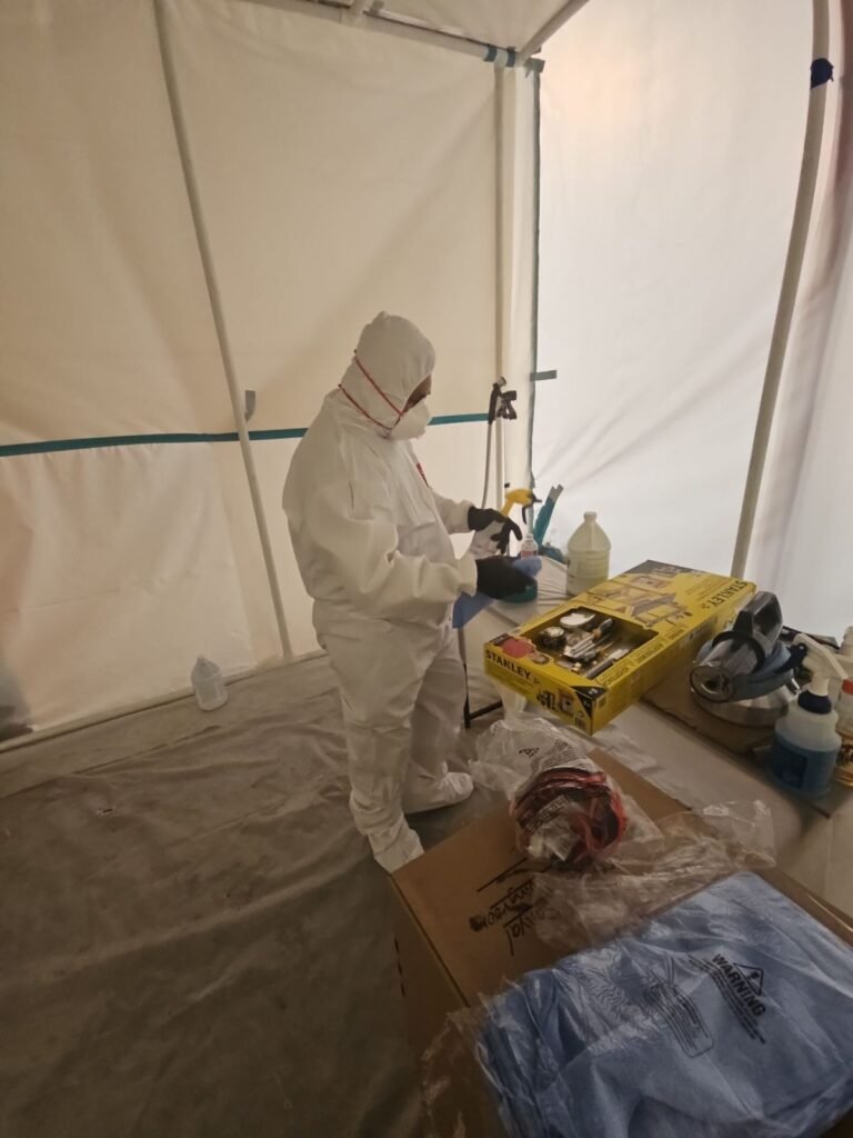 A technician working inside a fully sealed containment chamber in the East Bay