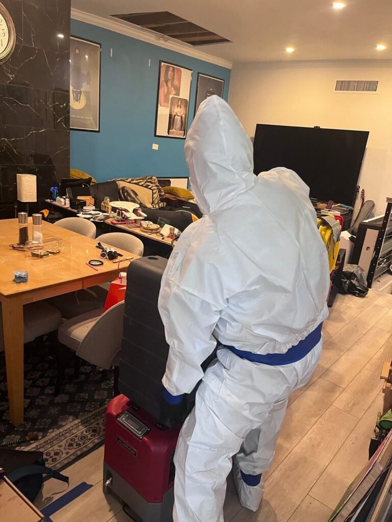 A suited technician working in a furnished dining room with a dehumidifier running in the East Bay