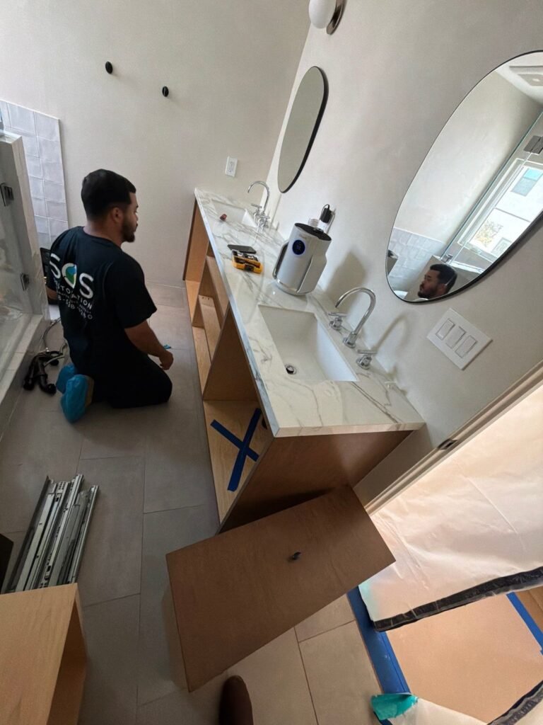 An SOS technician removing the vanity under a bathroom sink in the East Bay