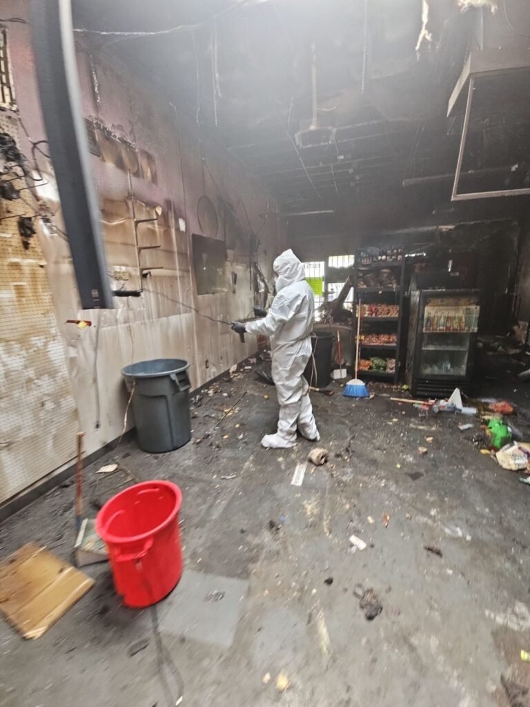 A technician working inside a burned-out commercial interior with soot on every surface in the East Bay