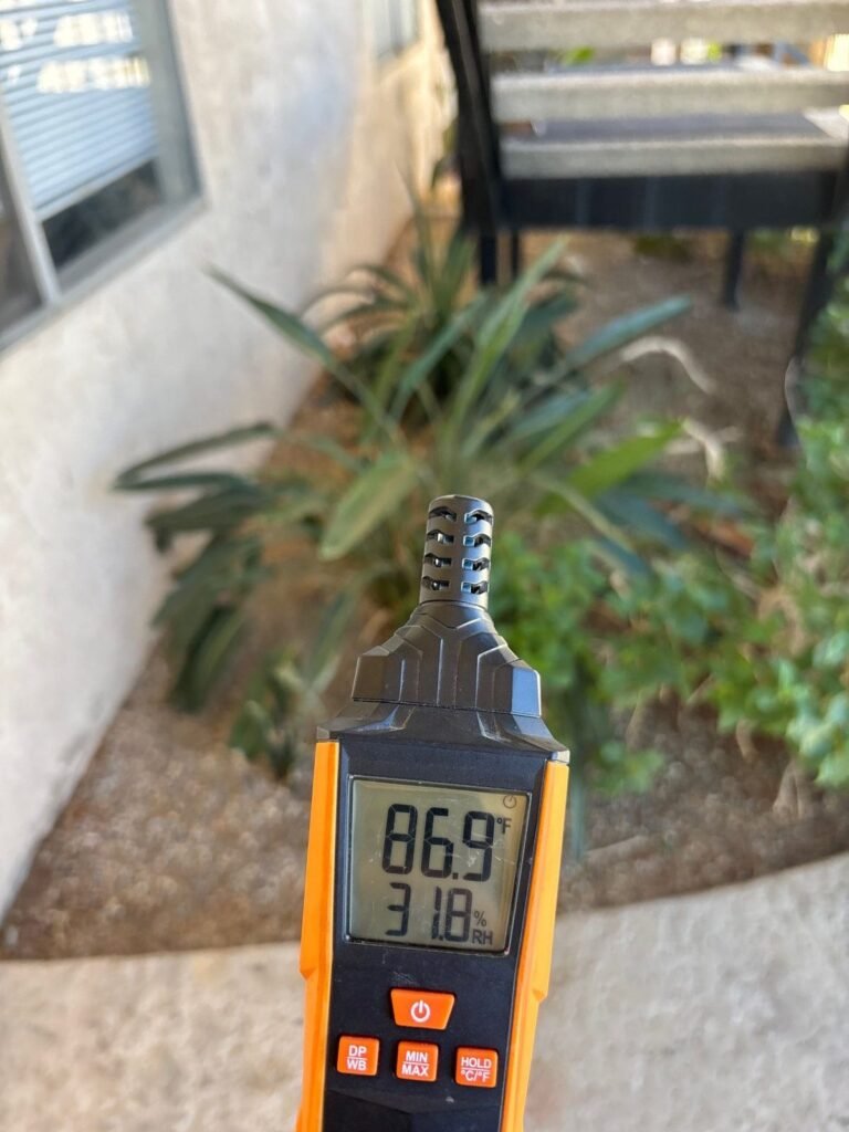A humidity meter reading 86.9 degrees outside beside the landscaping in the East Bay