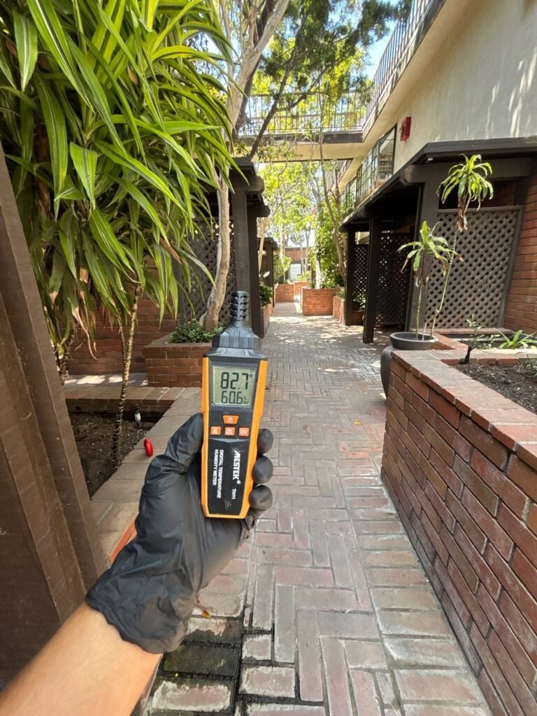 A humidity meter reading 82.7 in a side passage between buildings in the East Bay