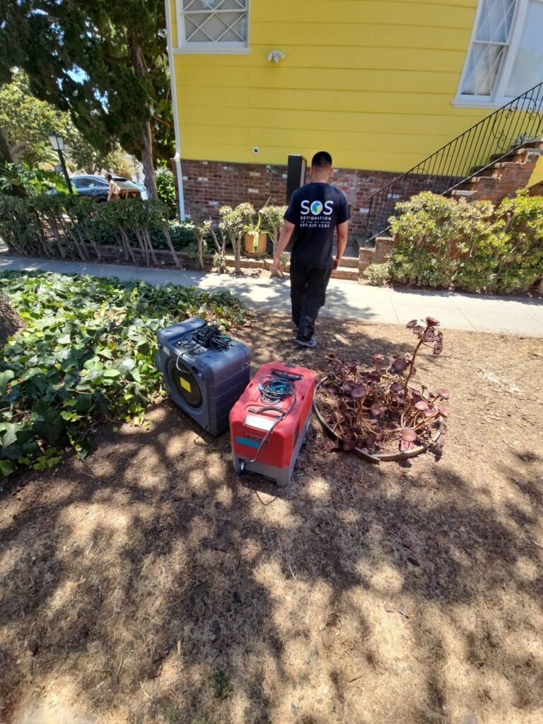 An SOS technician walking up to a house with a generator and equipment staged outside in the East Bay