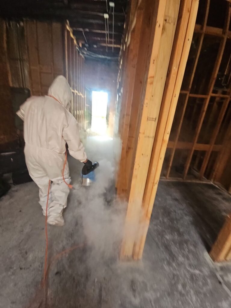A technician spraying antimicrobial in a hallway opened to the framing in the East Bay