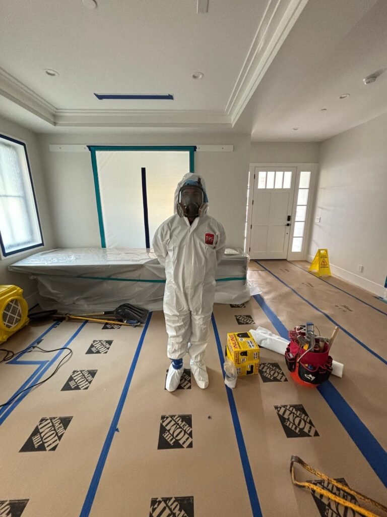 A suited technician standing in a large living room with the floor papered and taped in the East Bay
