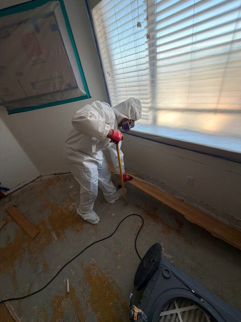 A technician working at the base of a wall under a shuttered window in the East Bay