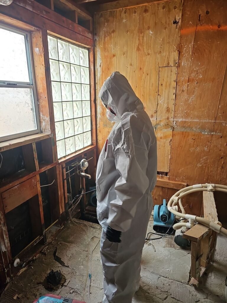 A technician beside a glass-block window in a room opened to bare wood in the East Bay